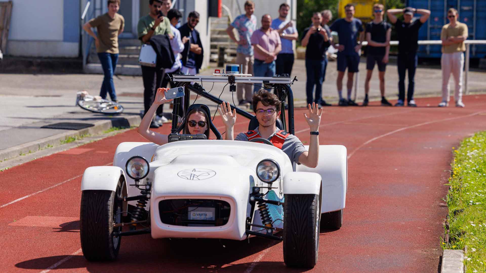 Les étudiants testent le véhicule autonome et lèvent leurs mains pour valider l'essai