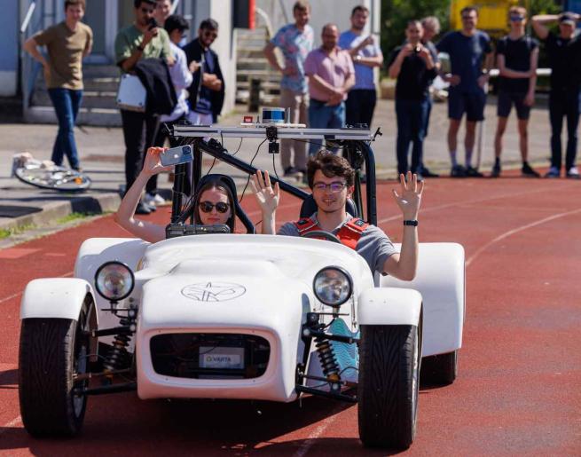 Les étudiants testent le véhicule autonome et lèvent leurs mains pour valider l'essai